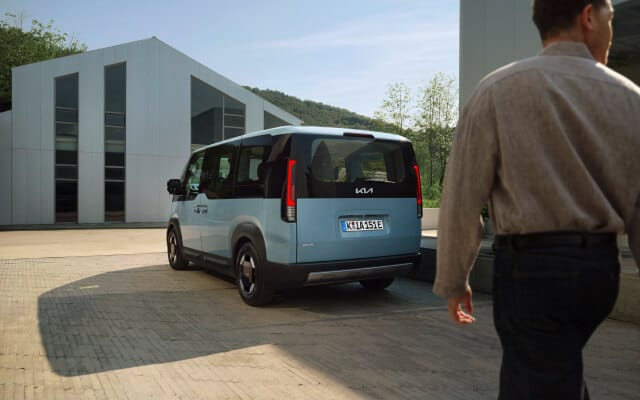 Seitenansicht des Kia PV5 Passenger, geparkt neben einer Wallbox.